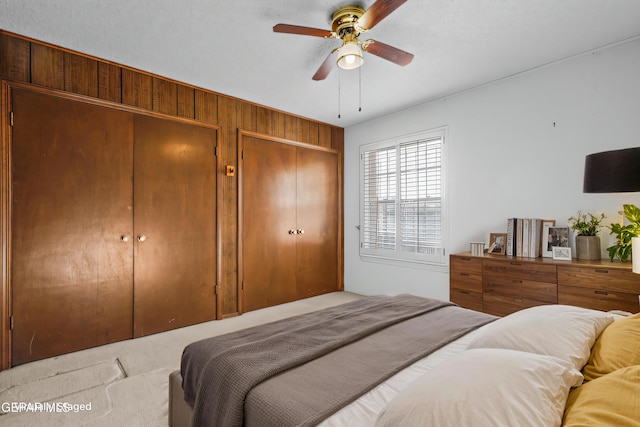 carpeted bedroom featuring multiple closets and ceiling fan