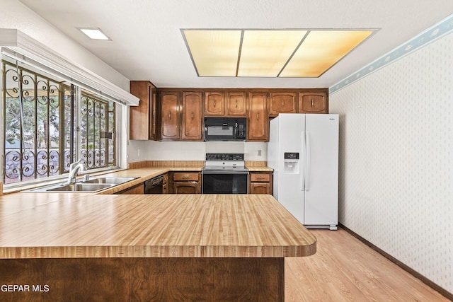 kitchen with sink, light hardwood / wood-style flooring, black appliances, and kitchen peninsula