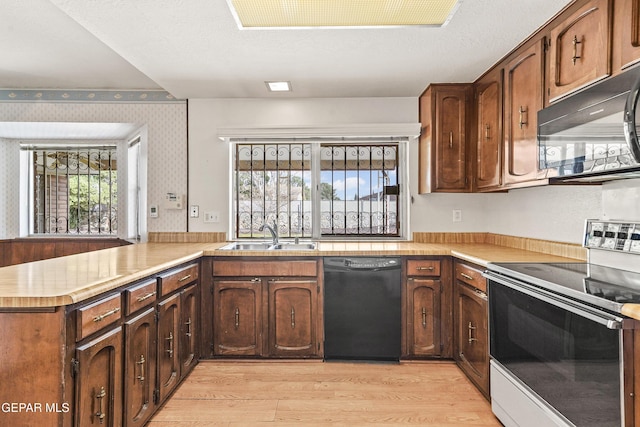 kitchen featuring sink, black appliances, a textured ceiling, kitchen peninsula, and light wood-type flooring