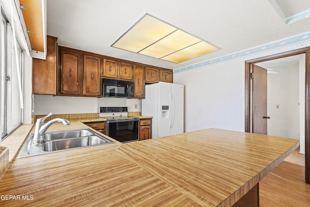 kitchen with range with electric stovetop, sink, white refrigerator with ice dispenser, light hardwood / wood-style floors, and kitchen peninsula