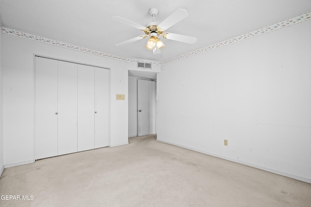 unfurnished bedroom featuring ceiling fan, light colored carpet, and a closet