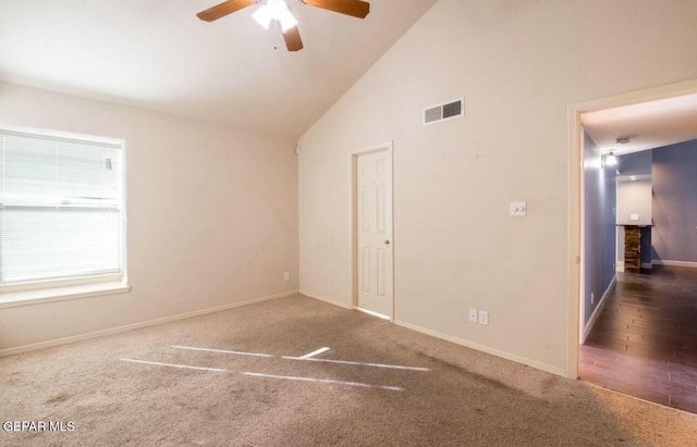 empty room featuring high vaulted ceiling, ceiling fan, and dark colored carpet