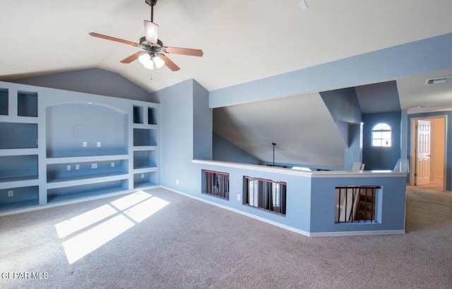 unfurnished living room featuring lofted ceiling, built in shelves, light carpet, and ceiling fan