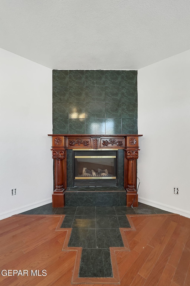 room details with a textured ceiling, a fireplace, wood finished floors, and baseboards