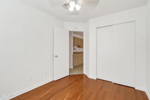 unfurnished bedroom with a sink, visible vents, baseboards, a closet, and light wood finished floors