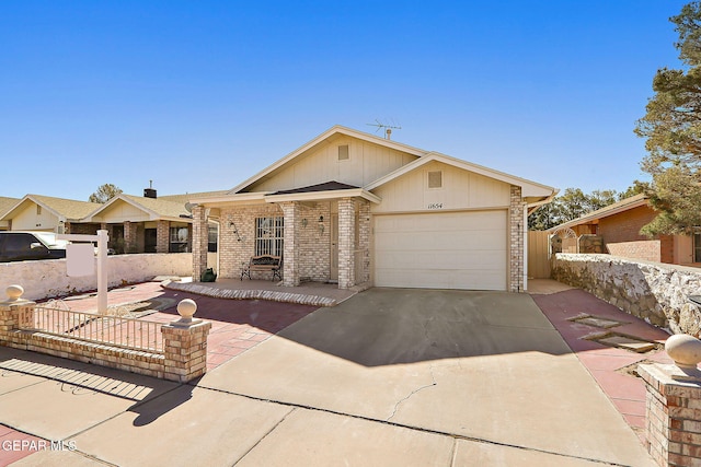 view of front of house with a garage, concrete driveway, brick siding, and fence