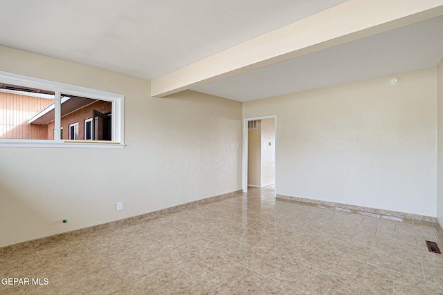 unfurnished room with beam ceiling