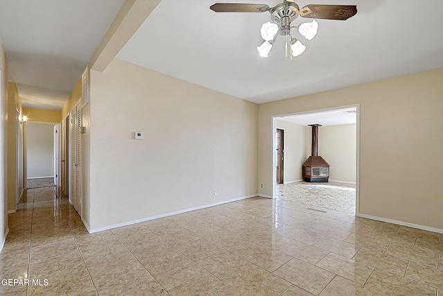 tiled empty room with a wood stove and ceiling fan