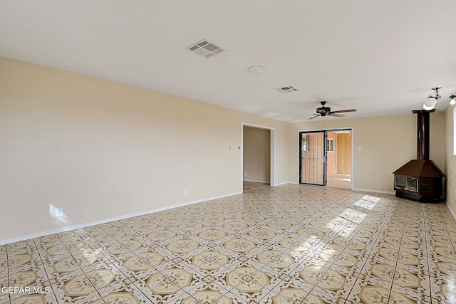 unfurnished living room featuring ceiling fan and a wood stove