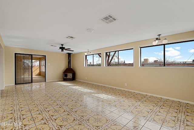 unfurnished room featuring ceiling fan and a wood stove