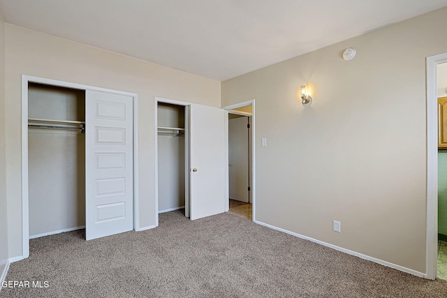 unfurnished bedroom featuring carpet and two closets