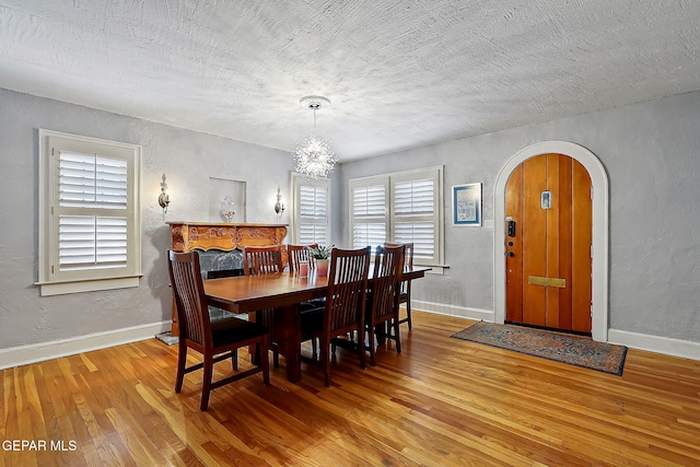 dining space featuring wood-type flooring, a textured ceiling, and a chandelier