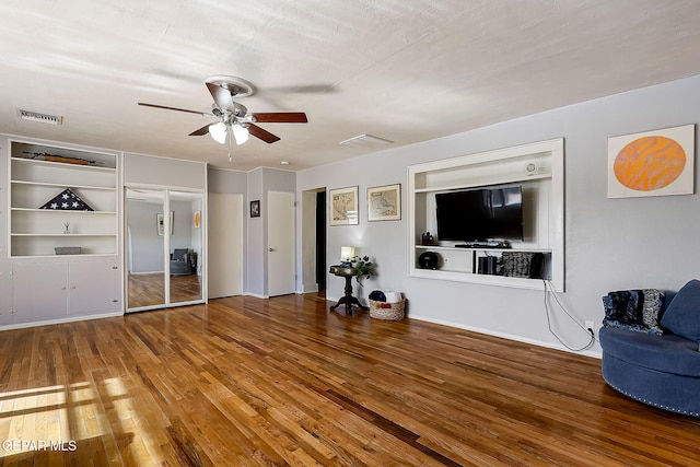 living room with wood-type flooring, built in features, and ceiling fan