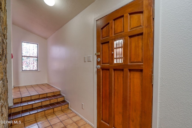 foyer with lofted ceiling and light tile patterned floors