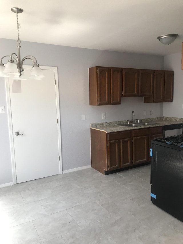 kitchen with stove, sink, dark brown cabinetry, and decorative light fixtures