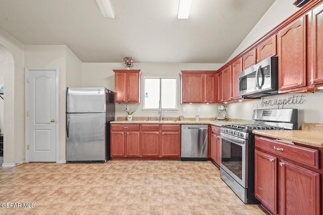 kitchen with vaulted ceiling, stainless steel appliances, and sink