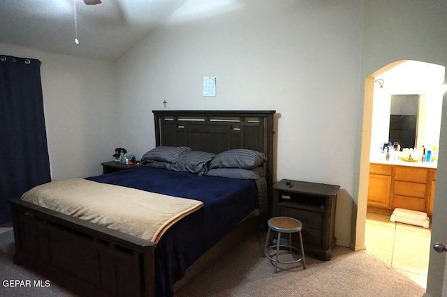 bedroom with ensuite bath, vaulted ceiling, and carpet