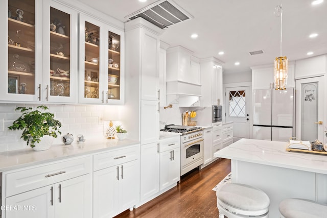 kitchen with pendant lighting, white appliances, premium range hood, light stone countertops, and dark hardwood / wood-style flooring