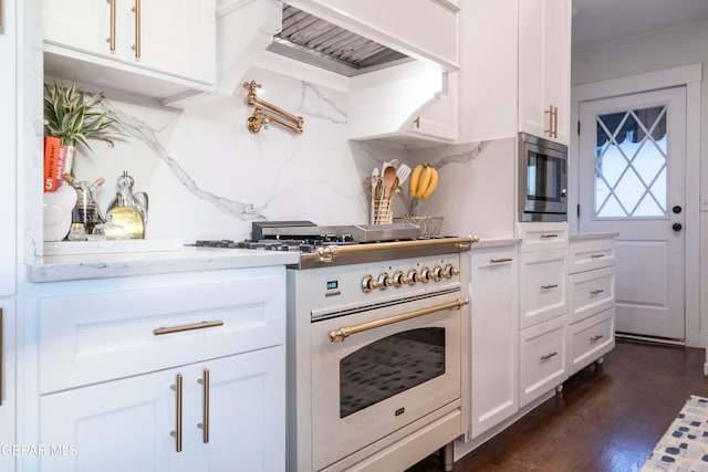 kitchen with dark hardwood / wood-style floors, stainless steel microwave, white cabinetry, high end range, and light stone counters