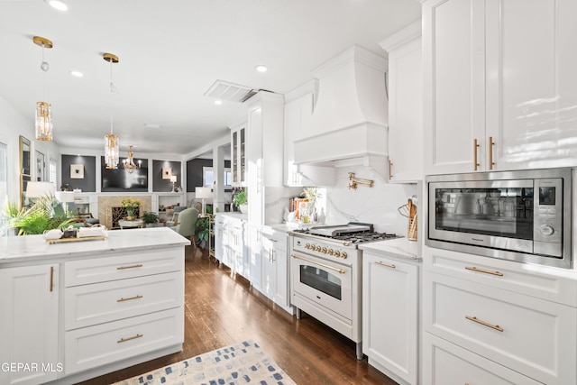 kitchen with light stone countertops, custom range hood, white range, and white cabinets