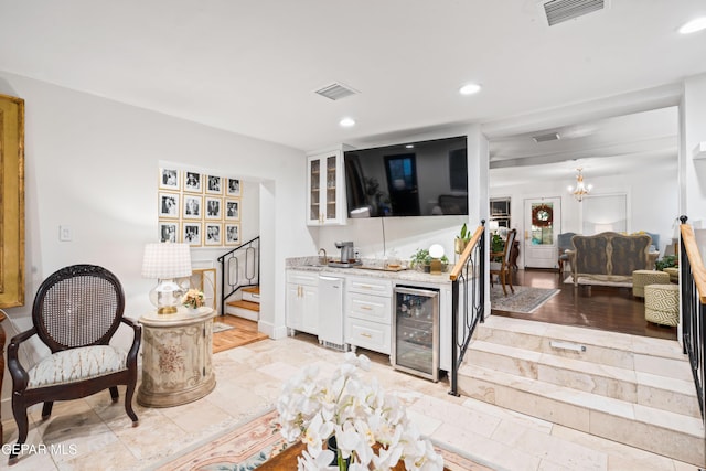 bar with white cabinetry, wine cooler, and an inviting chandelier