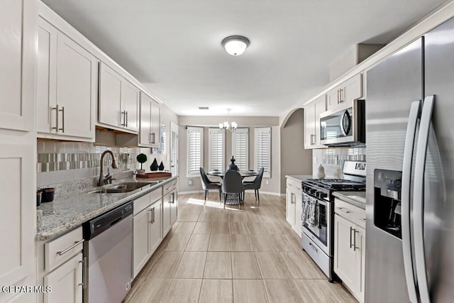 kitchen featuring pendant lighting, sink, white cabinetry, stainless steel appliances, and decorative backsplash