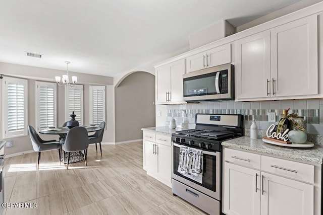 kitchen with white cabinetry, light stone countertops, decorative backsplash, and stainless steel appliances