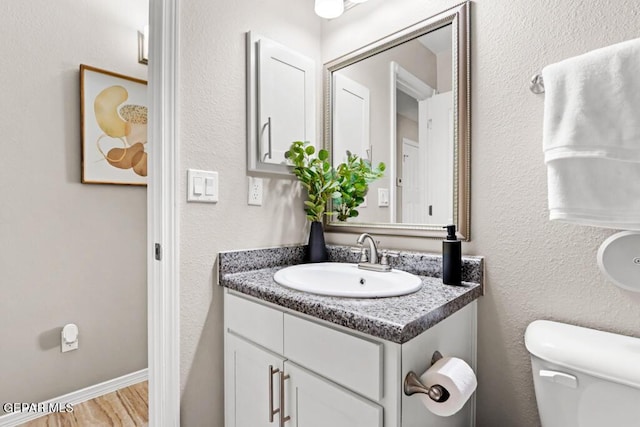 bathroom with vanity, toilet, and hardwood / wood-style floors