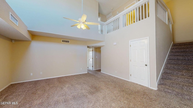 unfurnished living room featuring stairway, carpet flooring, visible vents, and a ceiling fan