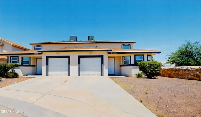 view of front of house with driveway, an attached garage, and stucco siding