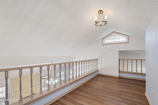 bonus room with an inviting chandelier, lofted ceiling, hardwood / wood-style floors, and a textured ceiling