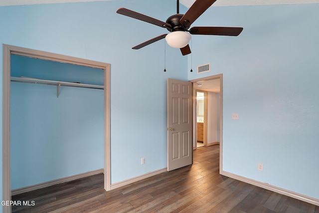 unfurnished bedroom with a towering ceiling, dark wood-type flooring, a closet, and ceiling fan