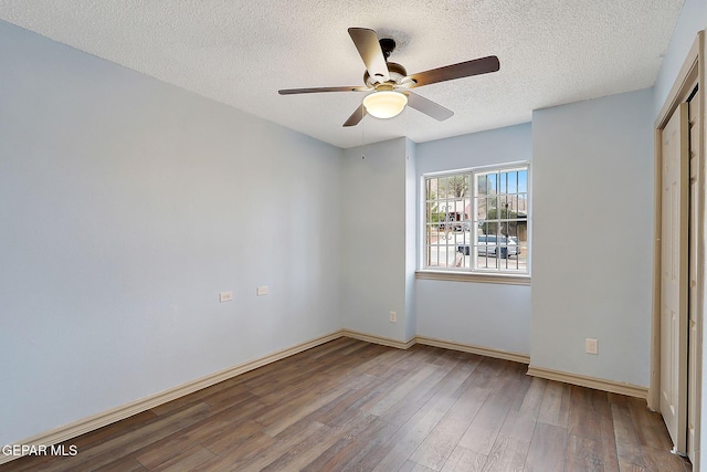 unfurnished bedroom featuring ceiling fan, hardwood / wood-style flooring, a closet, and a textured ceiling