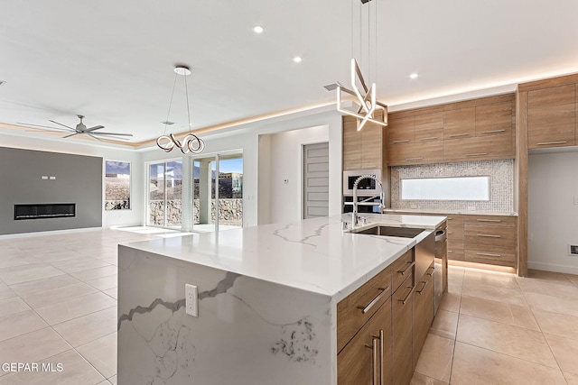 kitchen with light tile patterned flooring, decorative light fixtures, tasteful backsplash, and a large island with sink