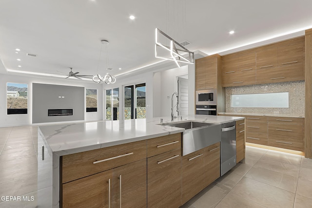 kitchen with a spacious island, sink, appliances with stainless steel finishes, a raised ceiling, and backsplash