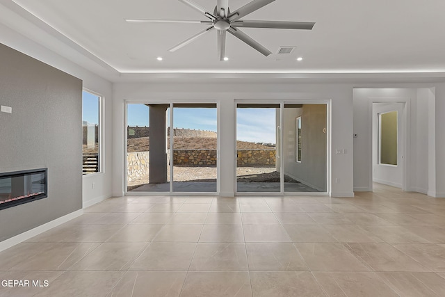 tiled spare room with a tray ceiling and ceiling fan