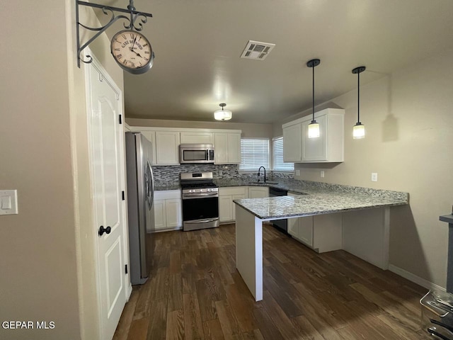 kitchen featuring kitchen peninsula, light stone counters, appliances with stainless steel finishes, white cabinets, and pendant lighting