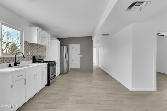 kitchen with sink, white cabinets, backsplash, stainless steel appliances, and light hardwood / wood-style flooring