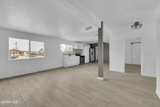 unfurnished living room featuring sink and light hardwood / wood-style flooring