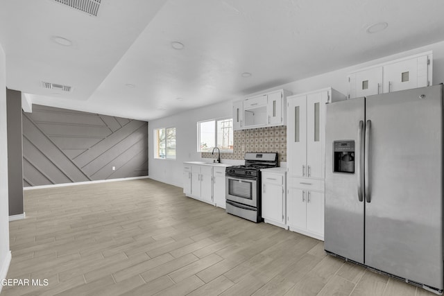 kitchen featuring sink, appliances with stainless steel finishes, tasteful backsplash, white cabinets, and light wood-type flooring