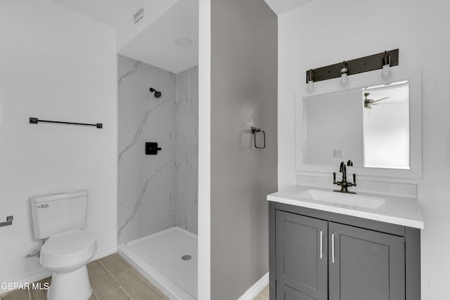 bathroom with a tile shower, vanity, and toilet