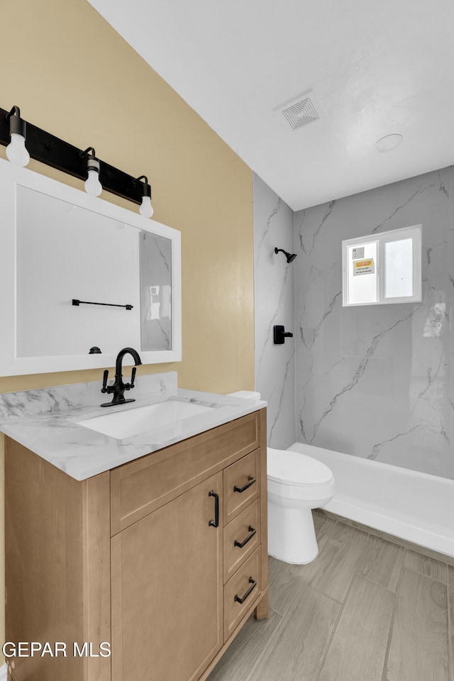 bathroom with tiled shower, vanity, and toilet