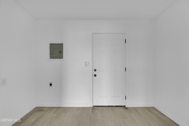 empty room with electric panel and light hardwood / wood-style floors