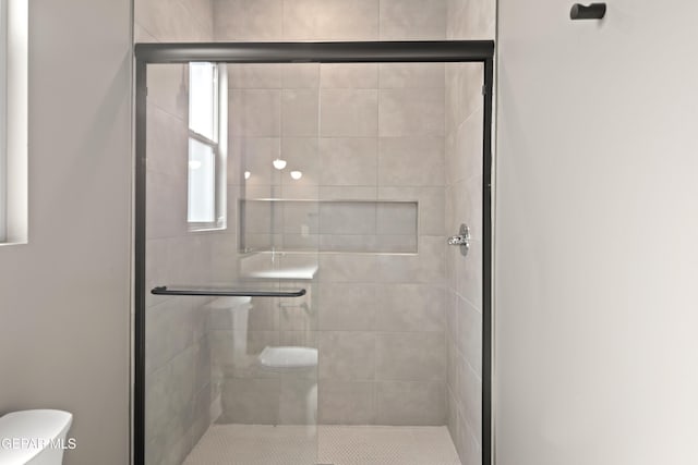 bathroom featuring toilet and a shower with shower door