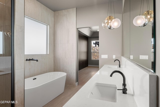 bathroom featuring vanity, wood-type flooring, tile walls, and a tub to relax in