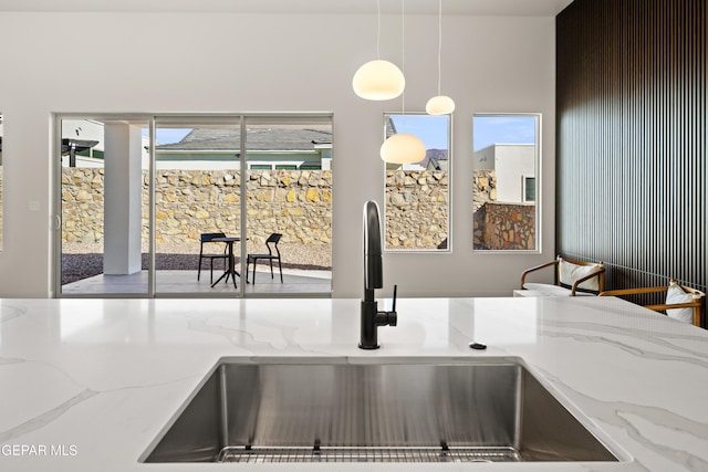 details featuring pendant lighting, sink, and light stone countertops