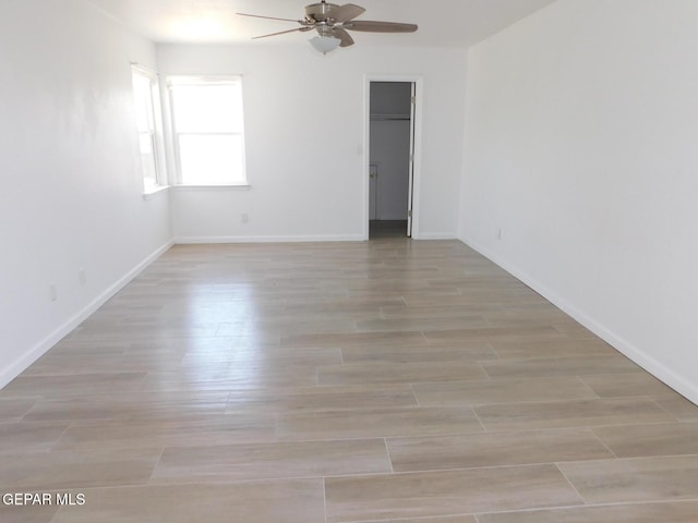 unfurnished room with baseboards, light wood-style flooring, and ceiling fan