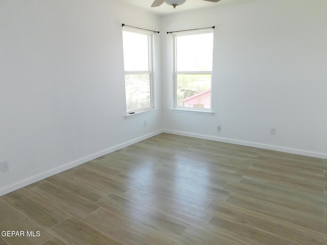 empty room with baseboards, ceiling fan, and wood finished floors