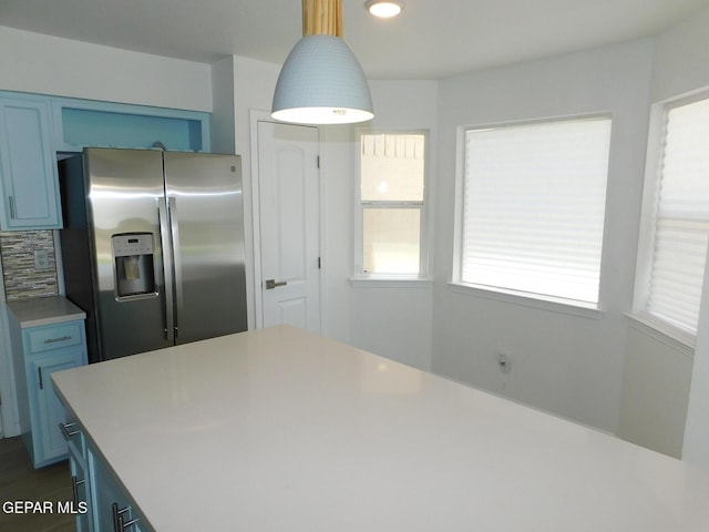 kitchen with stainless steel fridge, blue cabinets, and a wealth of natural light