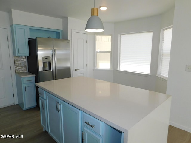 kitchen featuring light countertops, blue cabinetry, decorative light fixtures, and stainless steel fridge with ice dispenser